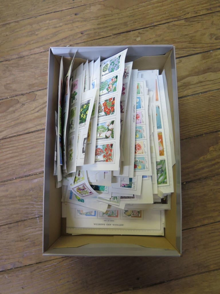 A box of mounted world postage stamps depicting flora, trees and fruit