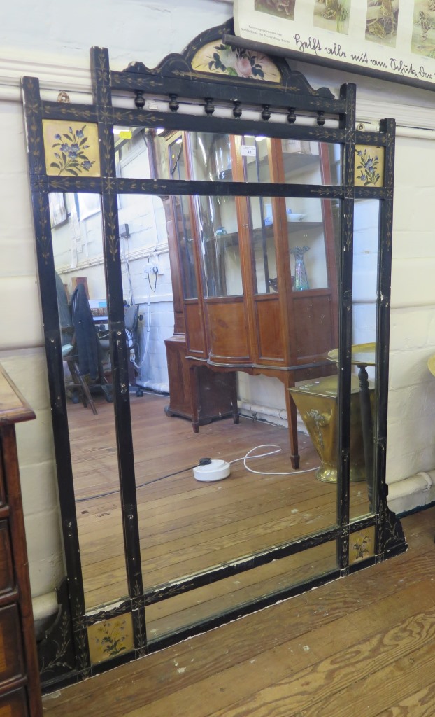 A late Victorian ebonised overmantel mirror, with gilded panels of flowers, now lacks side shelves