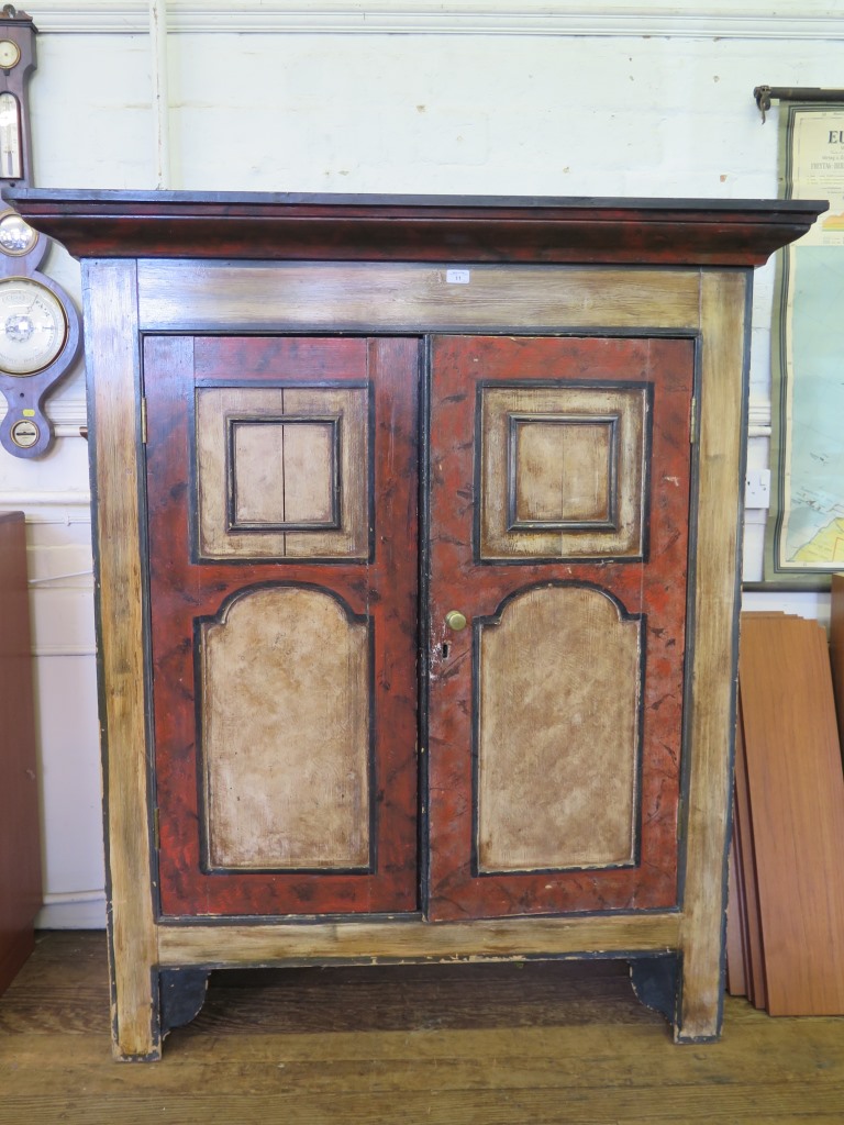 An Alpine style painted pine cupboard, the moulded cornice over a pair of panelled cupboard doors on