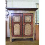 An Alpine style painted pine cupboard, the moulded cornice over a pair of panelled cupboard doors on