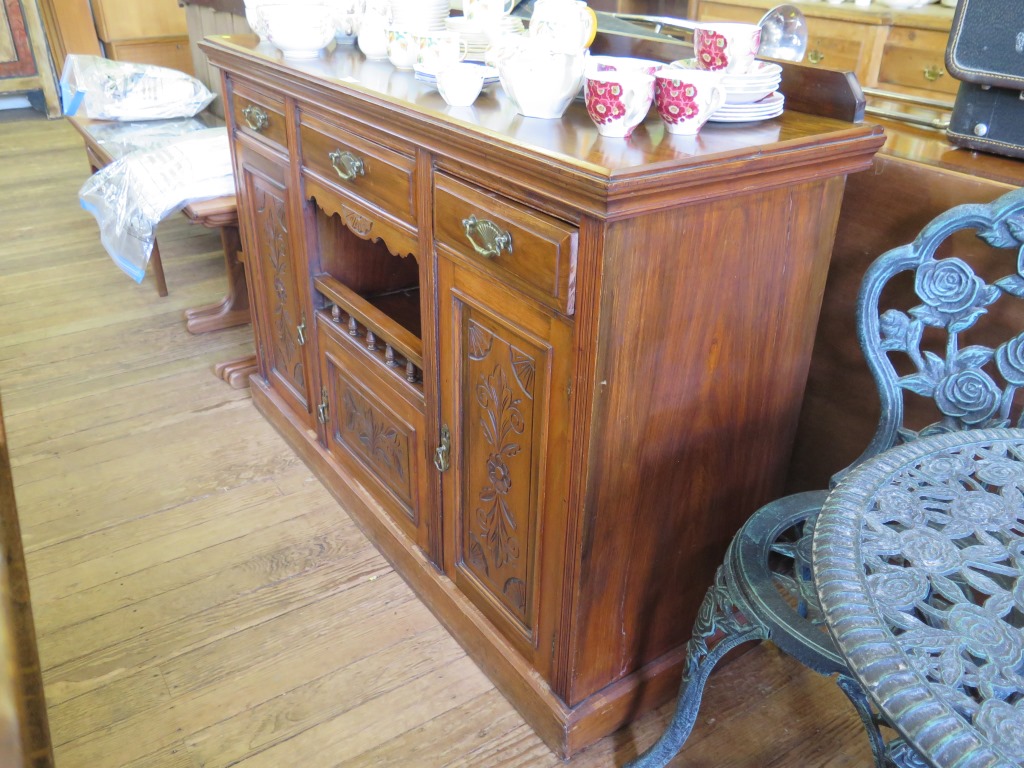 An Edwardian walnut sideboard, with three drawers over three cupboards and open space on a plinth