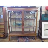 A mahogany and boxwood inlaid display cabinet, the husk inlaid frieze over a pair of glazed doors on