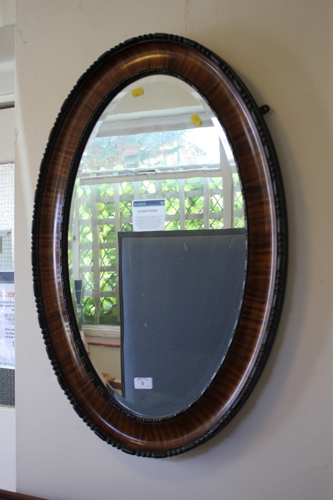 A stained wood oval wall mirror, with beaded frame and bevelled plate, 82 x 54cm