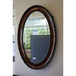 A stained wood oval wall mirror, with beaded frame and bevelled plate, 82 x 54cm