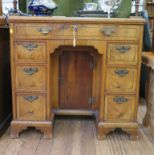 A George II crossbanded walnut kneehole desk with leather inset top over a long drawer over six