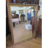 A giltwood framed wall mirror, with bevelled plate and foliate frame 86.5cm x 112cm *To be sold in