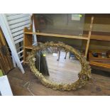 An Italian style gilt gesso wall mirror, the oval plate in a floral scroll frame 66cm x 49cm and a