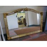 A reproduction Italian style giltwood wall mirror, with arched top and mirrored scroll motif