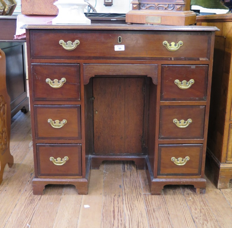 A George III crossbanded mahogany kneehole desk, the top with indented corners over a long drawer