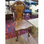A Victorian oak hall chair with C-scroll and shield carved back on cabriole legs