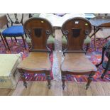 A pair of Victorian mahogany hall chairs, the C-scroll and shield backs over solid seats on