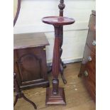 An Edwardian mahogany torchere stand, the circular top over a reeded and leaf carved stem on a