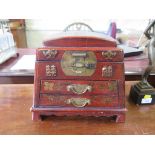 An Oriental red lacquered jewellery box, with hinged lid over two drawers and bracket feet 27cm