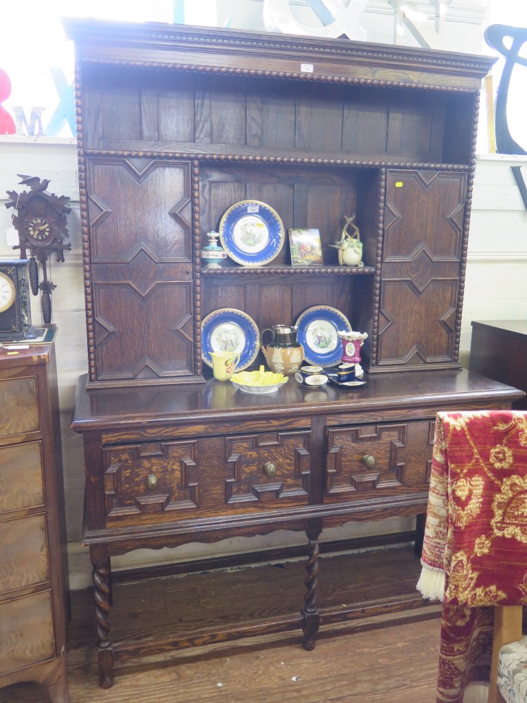 A Jacobean style oak dresser and rack, with panelled cupboard doors over a pair of similarly