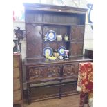 A Jacobean style oak dresser and rack, with panelled cupboard doors over a pair of similarly