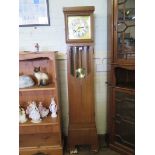 An Art Deco longcase clock, the brass and silvered dial over a bevelled glazed trunk, the three
