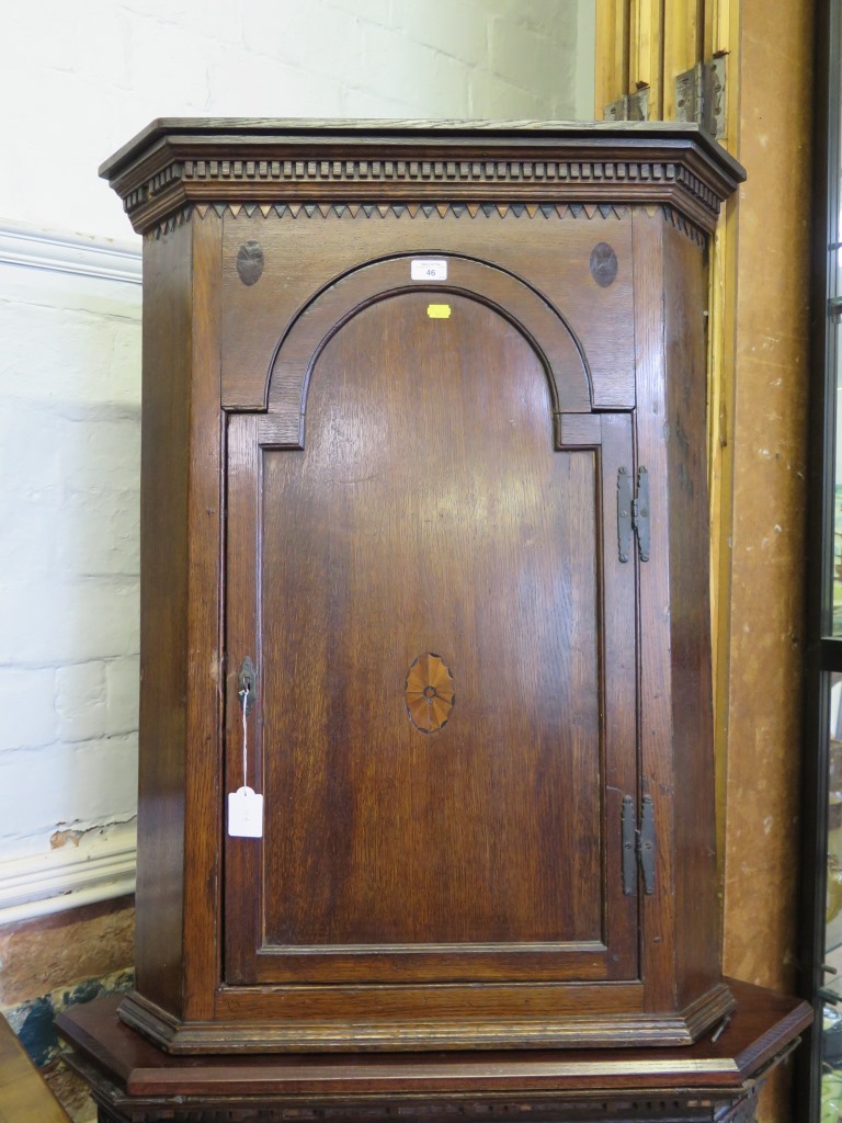 A George II oak corner cupboard, the dentil cornice over an arched door with patera inlay, 75cm wide