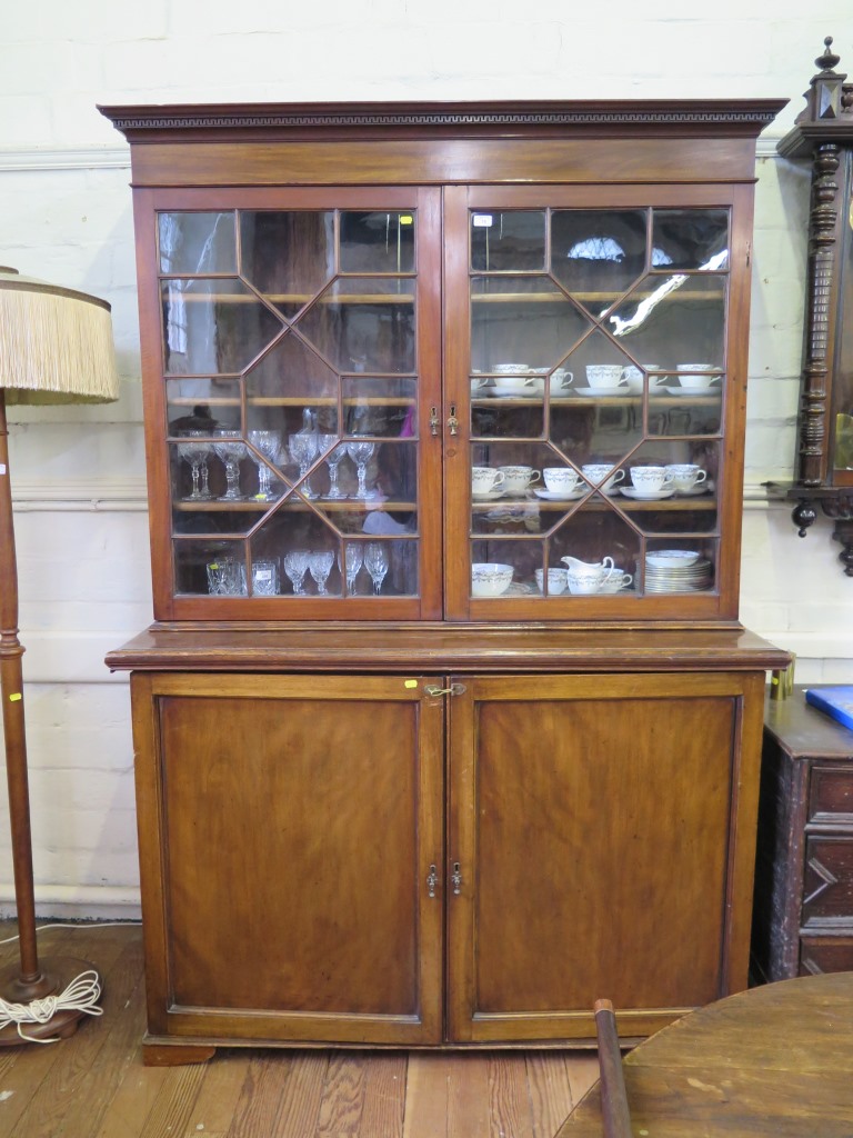 A George III style mahogany bookcase cabinet, the dentil cornice over a pair of astragal glazed