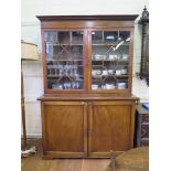 A George III style mahogany bookcase cabinet, the dentil cornice over a pair of astragal glazed