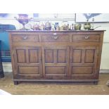 A George III oak dresser base, with three drawers over two panelled doors flanking a panelled centre