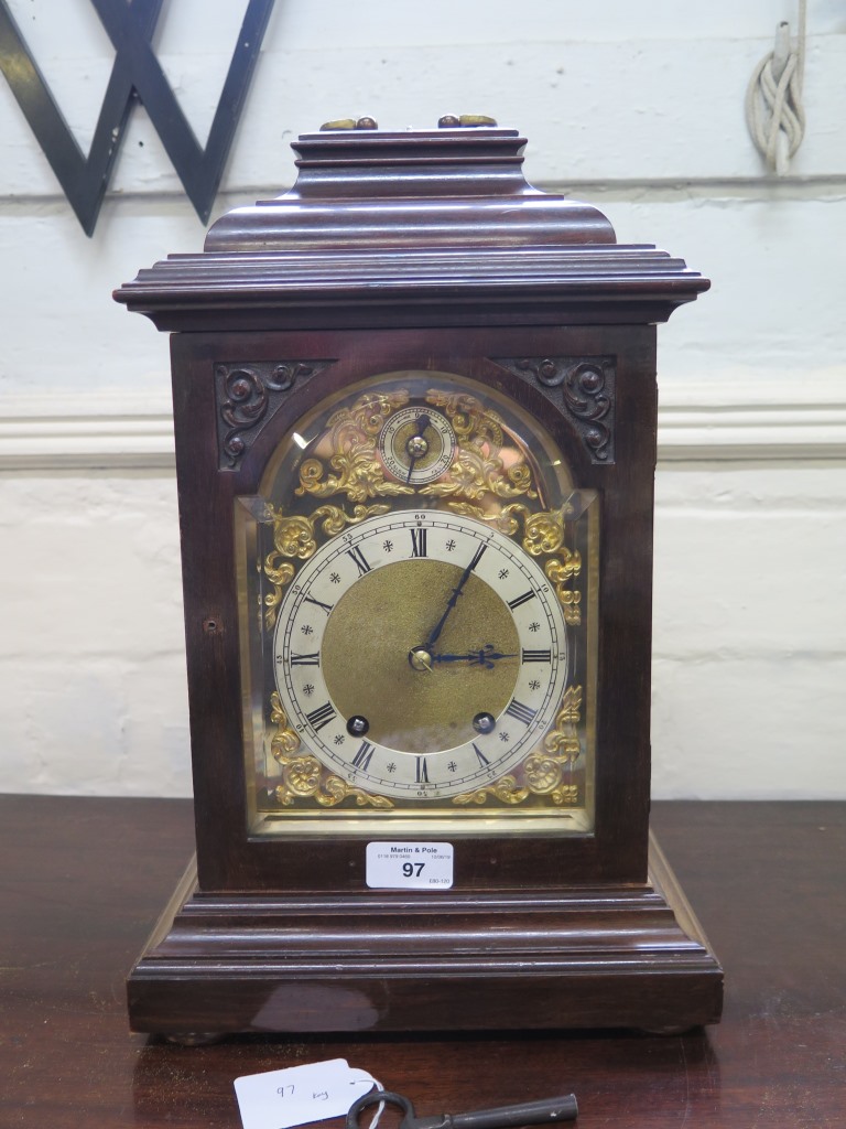 An Edwardian mahogany mantel clock in the George III style, the caddy top with brass handle over