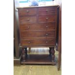 A small mahogany chest of drawers with four short and three long drawers, on turned legs, shelf
