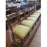 A set of six Edwardian walnut dining chairs, the moulded rail backs above overstuffed seats and ring