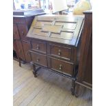 An 1930s oak bureau, the panelled slope enclosing pigeonholes over two graduated drawers on turned