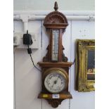 An Edwardian aneroid barometer with rosette and scroll carved frame and thermometer 59cm high