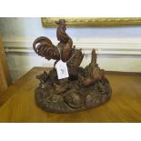 A North European carved wood figure of a cockerel and chickens among baskets, 25cm high