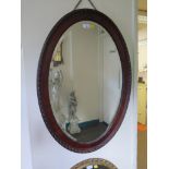 A mahogany framed oval wall mirror with bevelled plate 88cm x 62cm and an arched giltwood mirror (