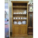 An oak bookcase cabinet with three adjustable shelves over a pair of cupboard doors and a plinth