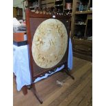An Edwardian firescreen, the fret carved top over a circular silk panel embroidered with flowers,