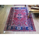A kazak style deep pile rug, the red field with geometric floral designs within a similar blue