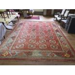 An Afghan carpet, the four rows of eight guls on a red field within a serrated border 412cm x 311cm