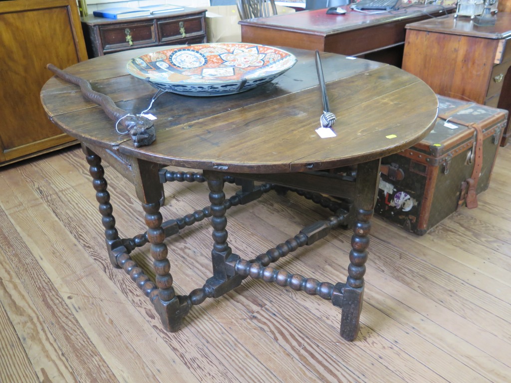 An 18th century oak gateleg table, the oval top over a foliate carved frieze and bobbin turned