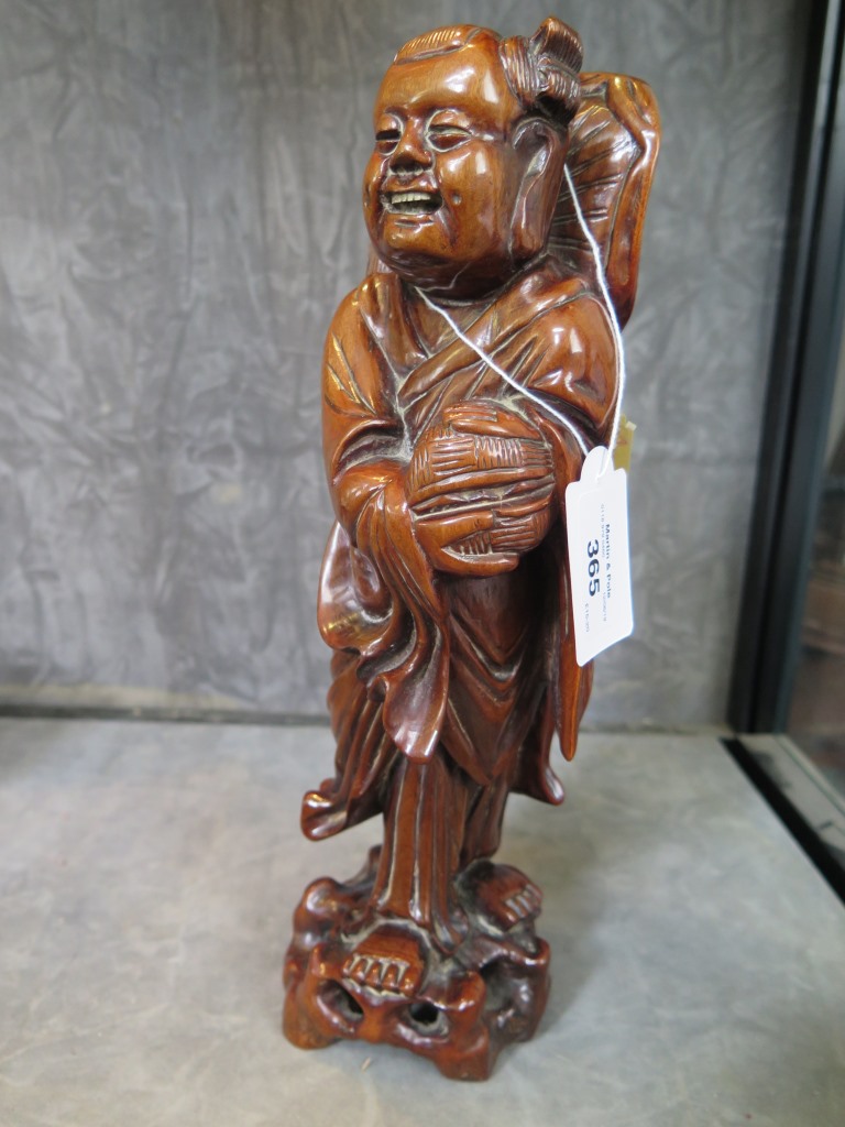 A Chinese carved wood figure of an elder holding a basket 30.5cm high