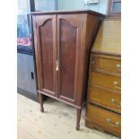 An Edwardian mahogany music cabinet, the twin doors enclosing three deep drawers, on square tapering