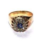 A continental gold ring set with a central sapphire within a rose diamond border