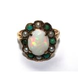 A 9 carat gold ring set with a central opal within a circle of alternating seed pearls and