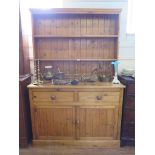 A pine dresser and associated rack, with two short drawers above a pair of panelled doors on a