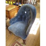 A Victorian button back armchair, in blue upholstery on moulded cabriole legs with pot castors