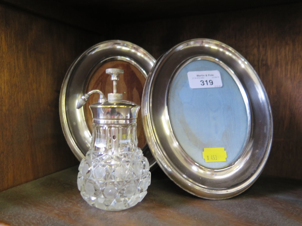 A pair of silver plated oval photo frames together with silver plated cut glass scent spray