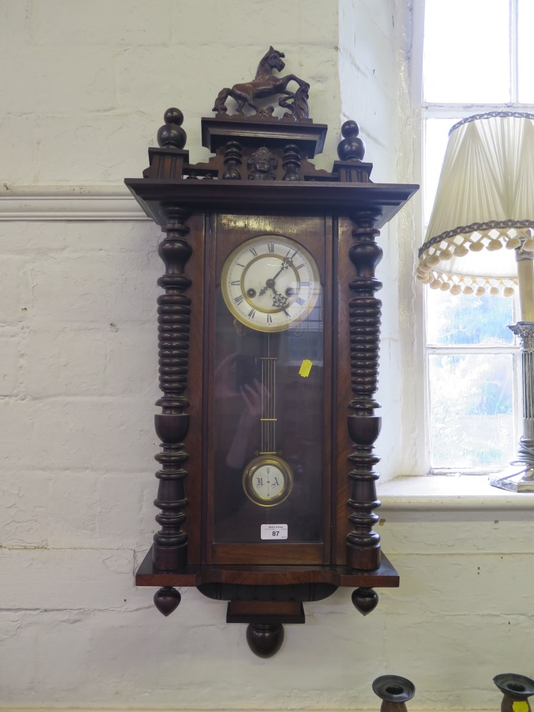 A 19th century walnut Vienna type wall clock, the mask and turned pediment surmounted by a horse,