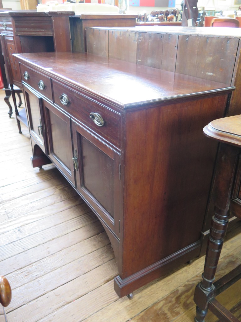 An Edwardian mahogany side cabinet, with two frieze drawers and three panelled doors, all with