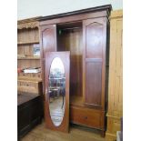 An Edwardian inlaid mahogany wardrobe, with oval mirrored door and long drawer 131cm wide, 52cm
