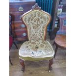 A Victorian walnut nursing chair, the carved crest over a waisted tapestry back and seat on