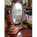 A Victorian mahogany toilet mirror, the oval plate on scroll supports over a shaped base with two