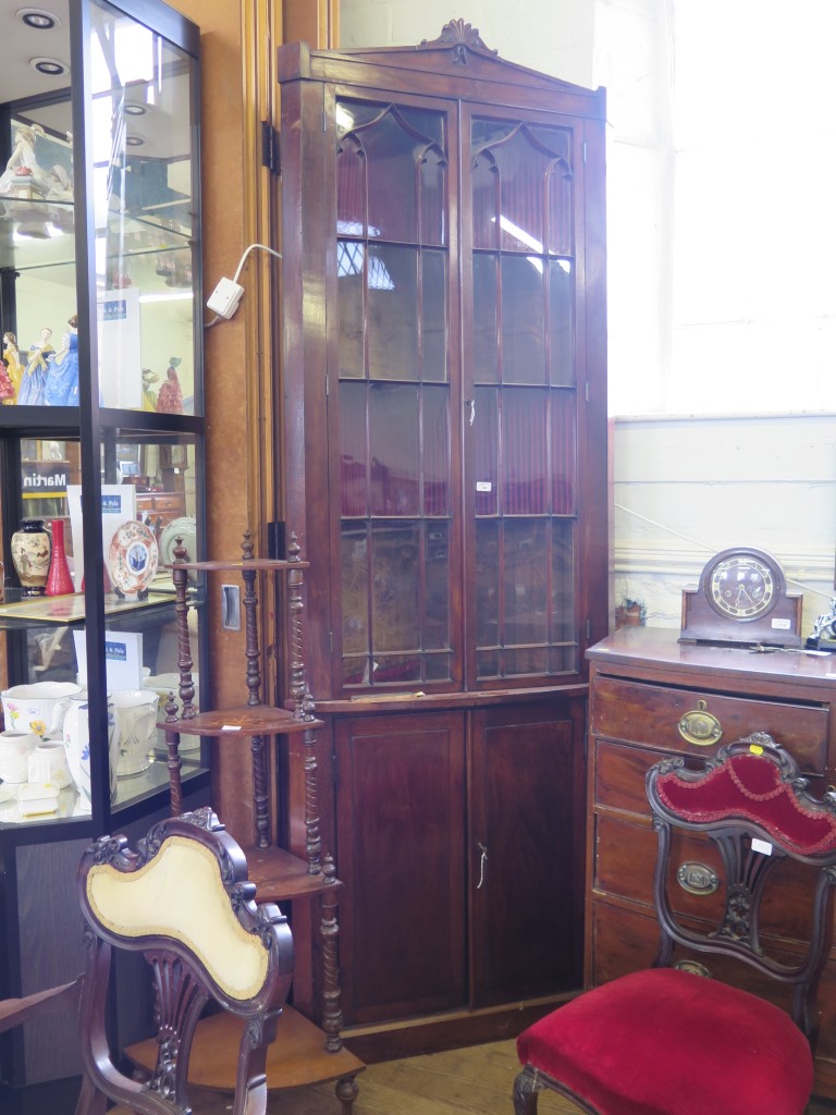 A tall early Victorian mahogany corner cabinet, the scroll carved pediment over a pair of glazed