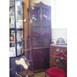 A tall early Victorian mahogany corner cabinet, the scroll carved pediment over a pair of glazed